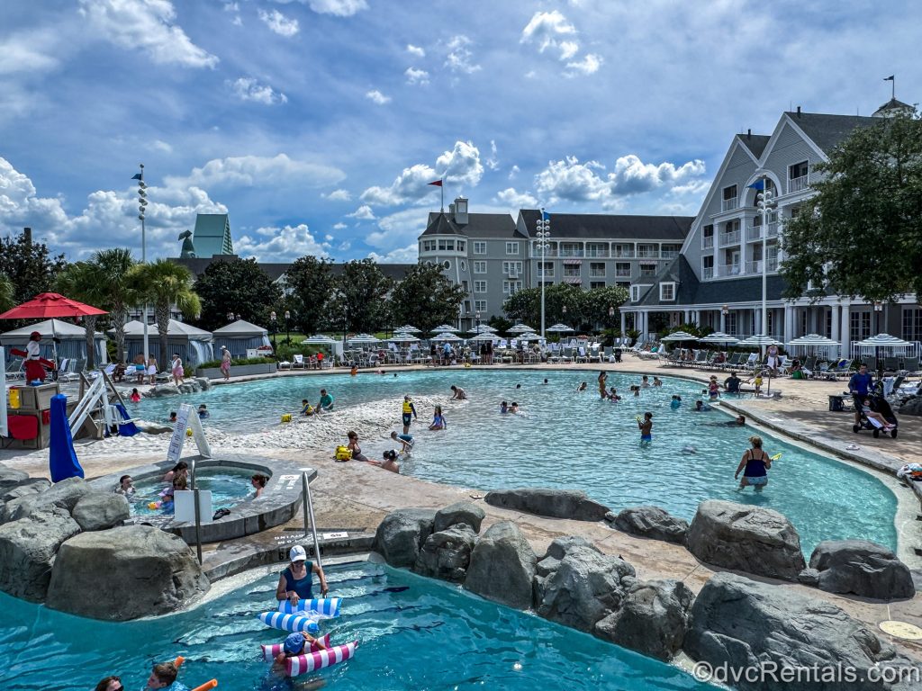 Guests enjoy the water, whirlpool spa, sun, and sand at Stormalong Bay at Disney’s Beach Club Villas under a sunny sky.