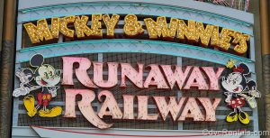 Neon lights displaying the attraction name “Mickey & Minnie’s Runaway Railway” along with depictions of Mickey and Minnie Mouse. The wording is in gold and pink.