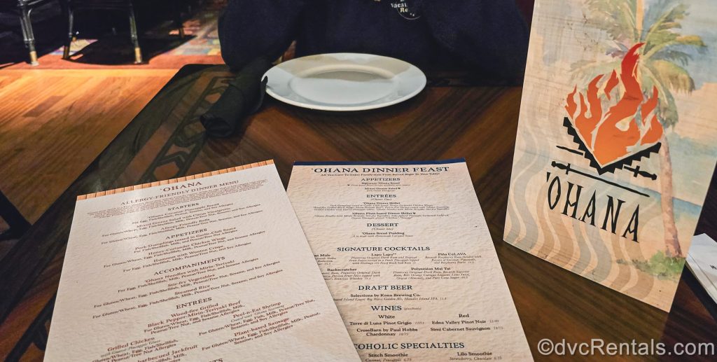 Standard and allergy friendly dinner menus are seen on a dark wood table at ‘Ohana at Disney’s Polynesian Villas & Bungalows.